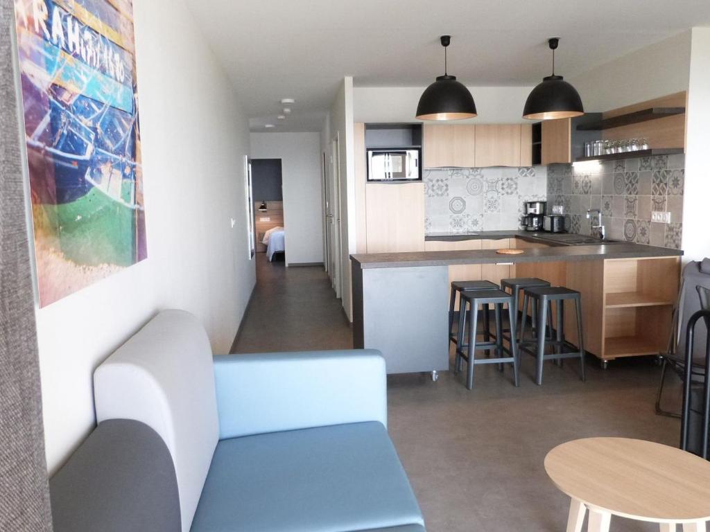 a living room and kitchen with a blue couch and a table at Appartement bord de mer avec accès plage, piscine, jacuzzi, 1 chambre, animaux admis, parking inclus - FR-1-194-253 in La Tranche-sur-Mer