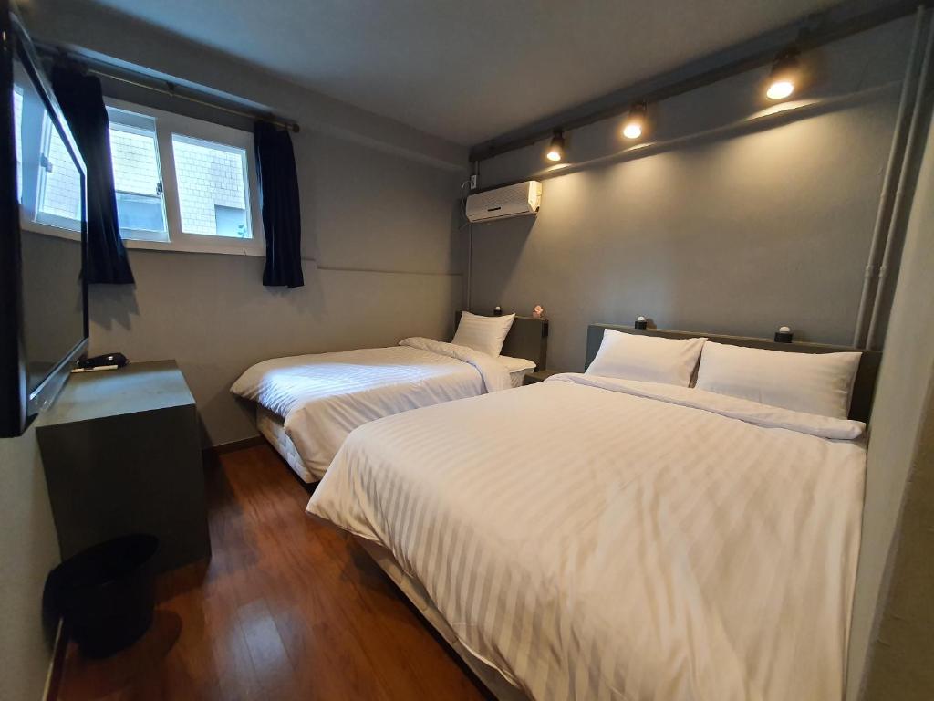 a room with two beds and a television in it at Daljee Guesthouse in Seoul