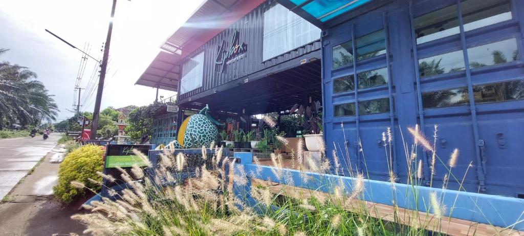 um edifício azul com plantas em frente em Kipbox Hotel Trang em Trang