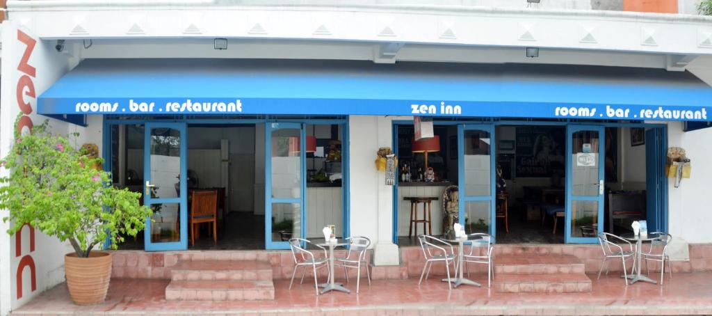 Zen inn في بادانجباى: مطعم أمامه طاولات وكراسي