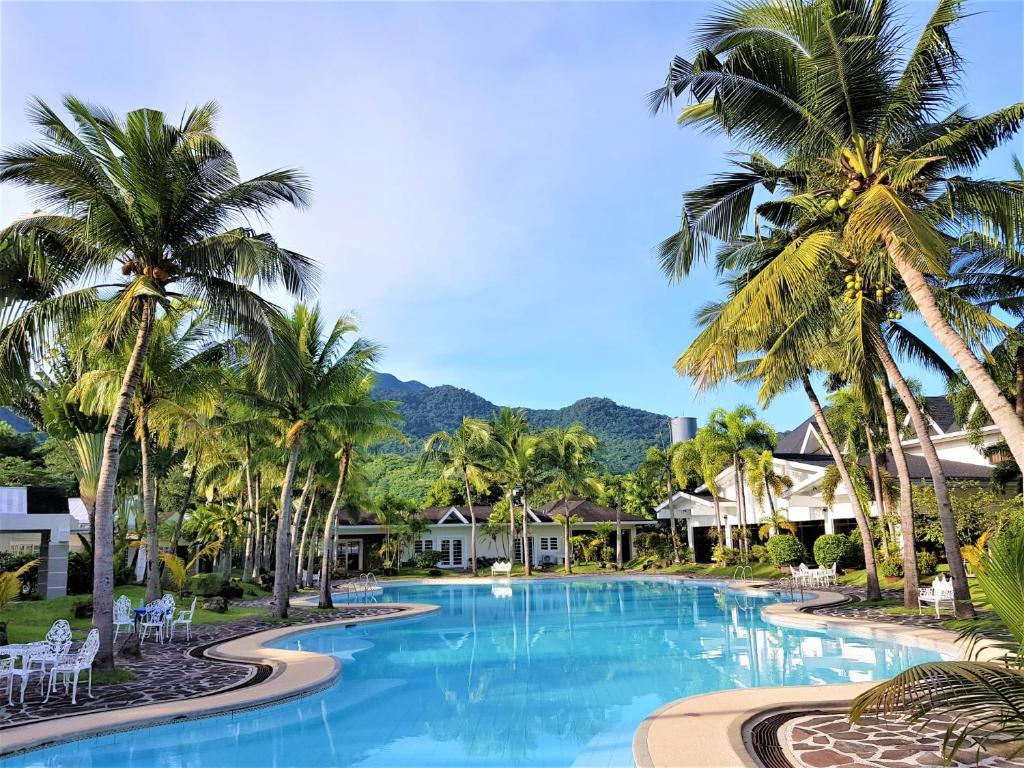 - une grande piscine avec des palmiers dans un complexe dans l'établissement Chateau Bleu Resort, à Calamba