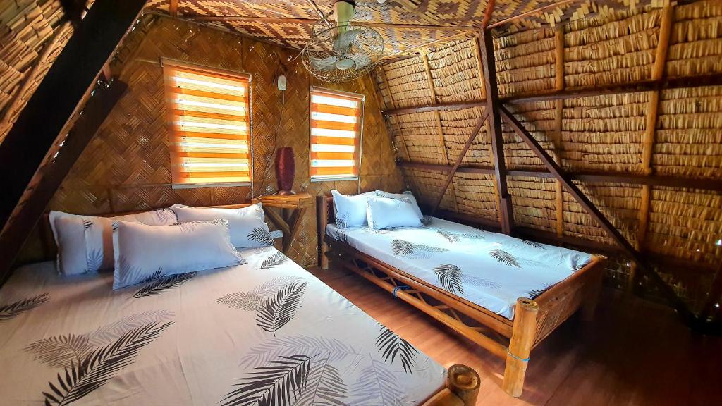 a room with two beds in a straw hut at Calatagan's Bahay Kubo - with Beach Access in Calatagan