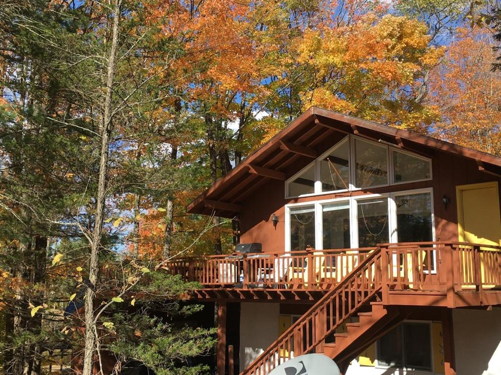 a cabin with a deck in the woods at Contemporary Magic Mountain Chalet Close to Skiing, Hiking, Fun in Londonderry