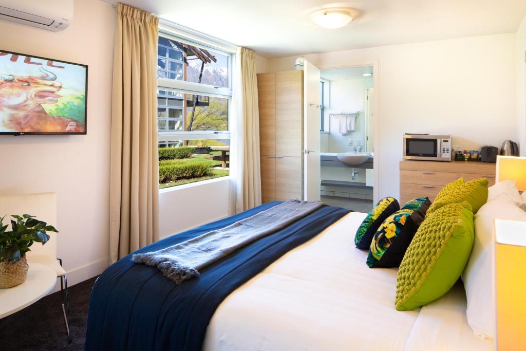 sypialnia z łóżkiem z poduszkami i oknem w obiekcie QS Marina w mieście Queenstown
