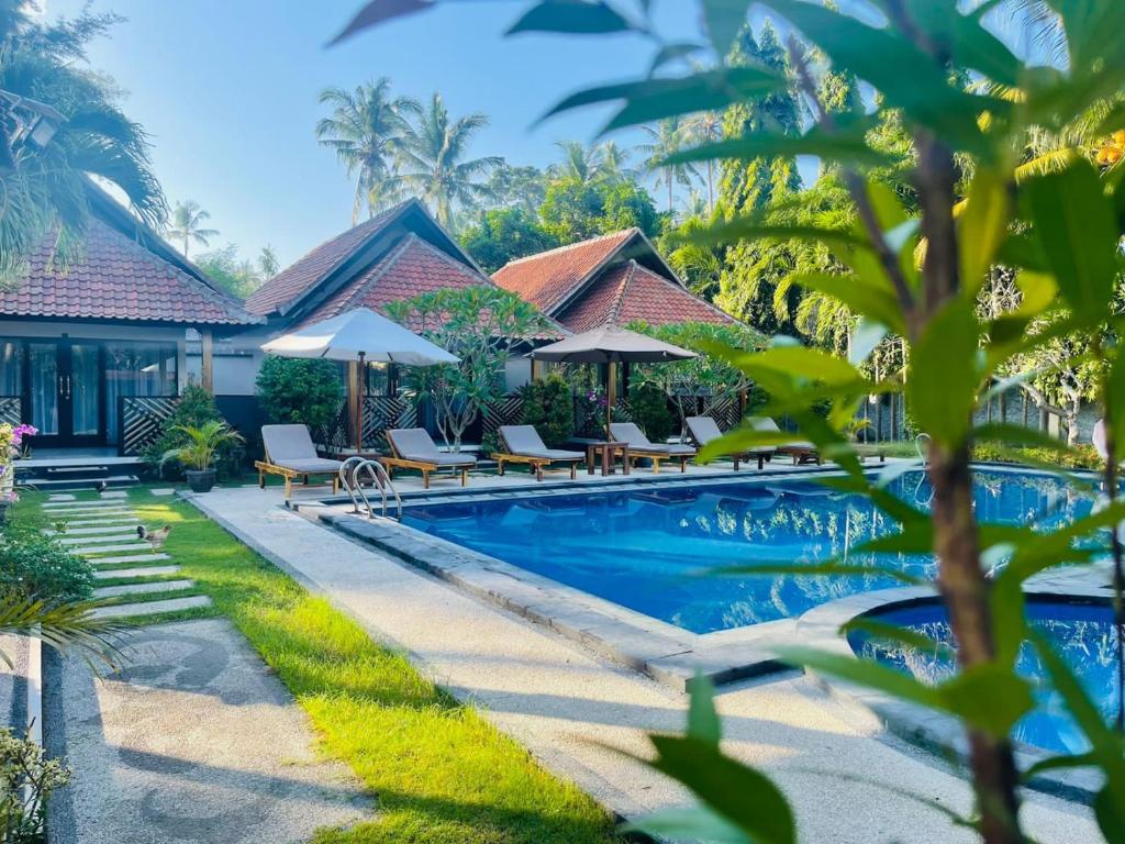 una piscina del resort con sedie e ombrelloni di Mutiara Bali a Candidasa