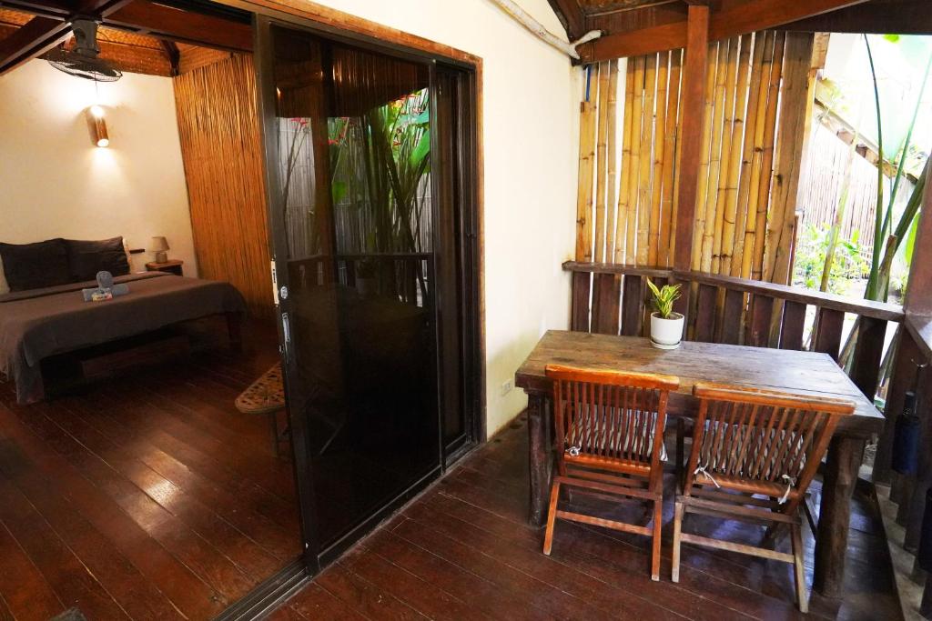 um quarto com uma mesa de madeira e cadeiras numa varanda em Fisheye The Rooms - Family room em El Nido