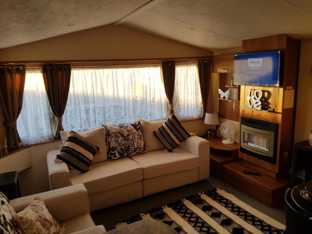a living room with a couch and a television at Caravan on Golden Gate Holiday Park in Kinmel Bay