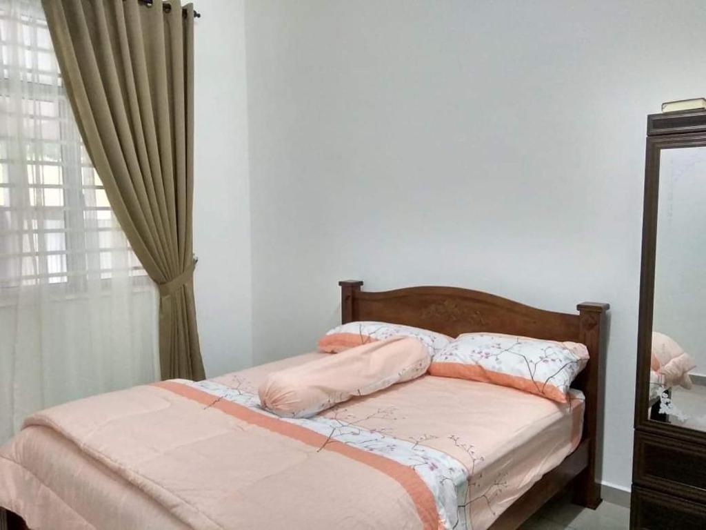 een slaapkamer met een bed met roze lakens en een spiegel bij FENDIONYA CORAL in Port Dickson
