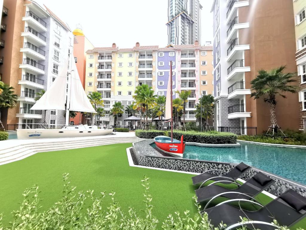a pool with a green lawn in front of some buildings at C24 Seven Seas Cote DAzur Luxury Private in Na Jomtien