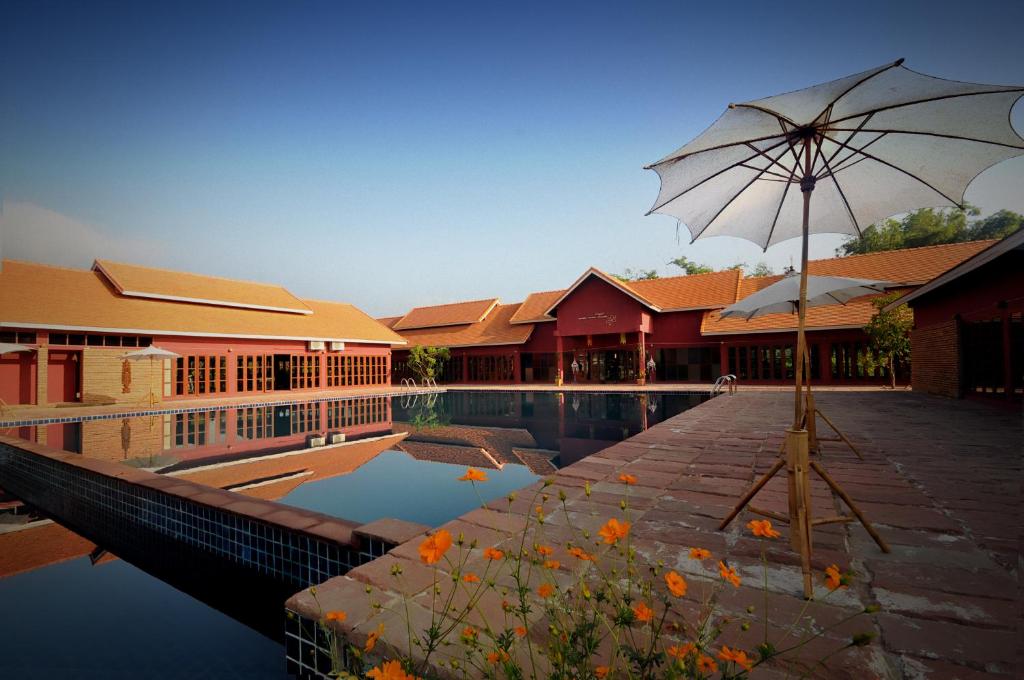 a pool with an umbrella next to a building at Chiangmai Royal Creek Hotel in Hang Dong