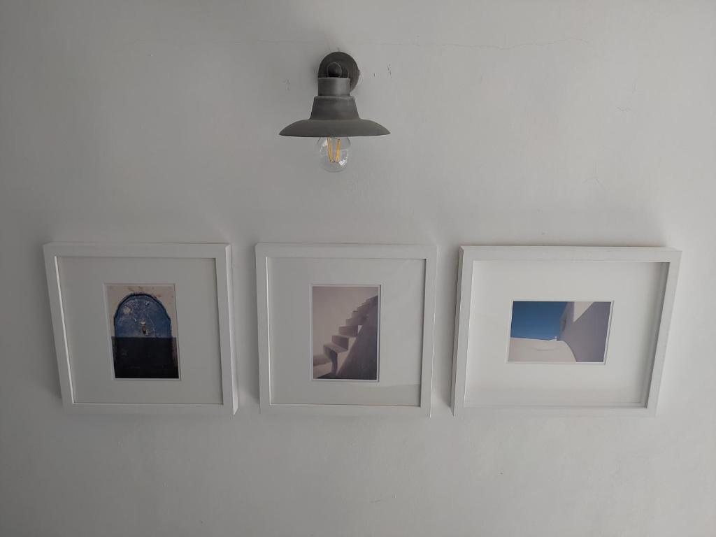 four pictures on a white wall with a lamp at Latmos 1860 in Skala