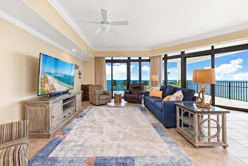 a living room with a blue couch and a flat screen tv at The Oasis at Orange Beach Condos by Hosteeva in Orange Beach
