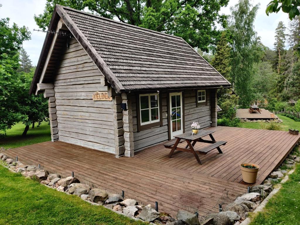 Cabaña de madera con mesa de picnic en la cubierta en Tiku Holiday Homes, en Kiidjärve
