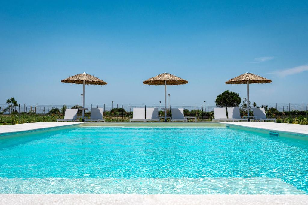 a swimming pool with chairs and umbrellas at Beach Bird Swallow in Megáli Panayía