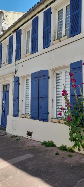 un edificio con puertas azules y ventanas con flores en Résidence Les Volets Bleus: Studio de 30 m² classé 2 *, en Rochefort
