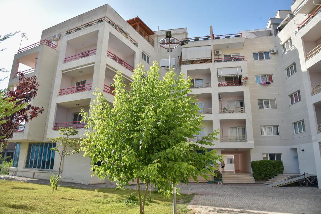 un edificio de apartamentos con un árbol delante de él en Flowers Apartments, en Golem