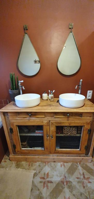 two sinks on a wooden vanity with two mirrors at Maison campagne chic in Biganos