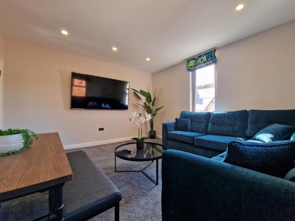 a living room with a blue couch and a tv at DYSA Clifton Apartments in Lytham St Annes