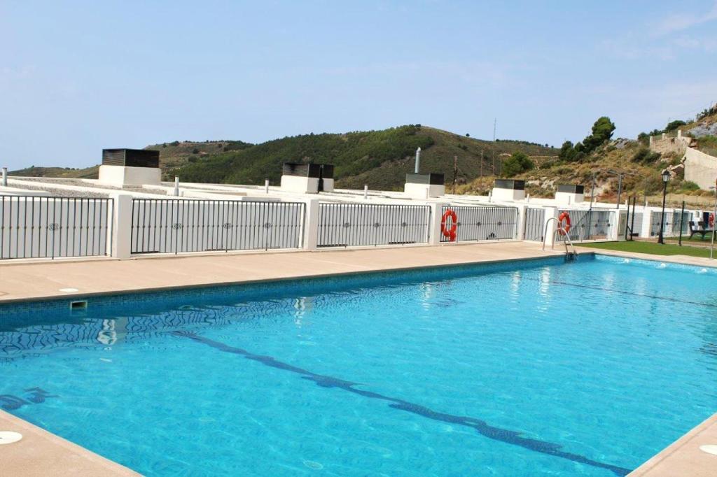 a large blue swimming pool with a hill in the background at 2 bedrooms apartement with shared pool enclosed garden and wifi at La Canada in La Cañada de San Urbano