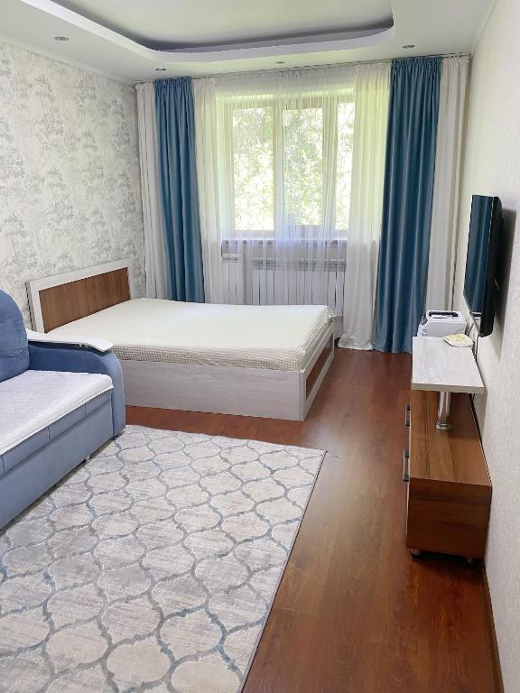 sypialnia z łóżkiem, telewizorem i kanapą w obiekcie Апартаменты аэропорт w mieście Ałma-Ata