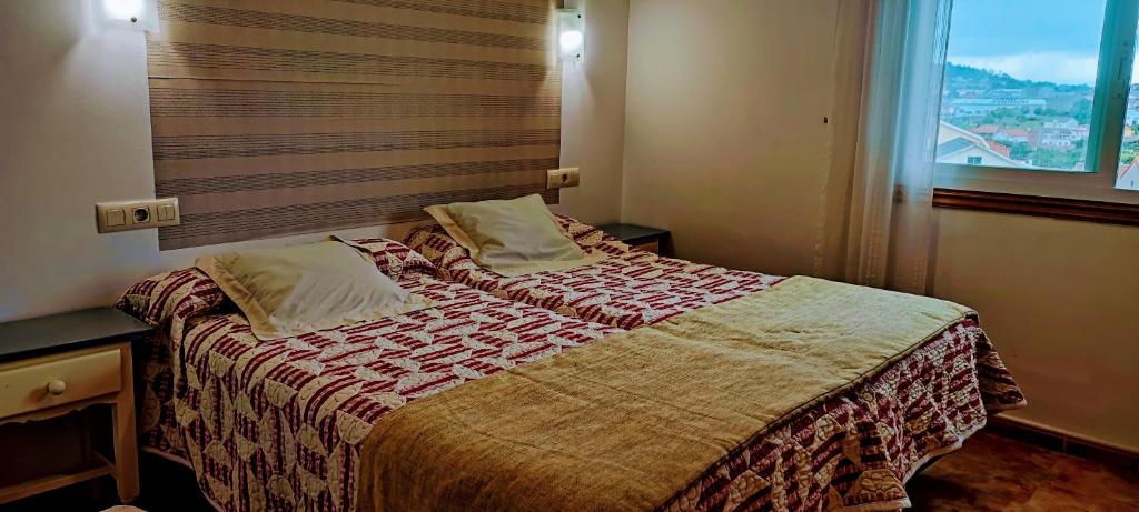 sypialnia z dużym łóżkiem i oknem w obiekcie Pisos Vistalegre 2B con jardín cerca del mar w mieście Sanxenxo