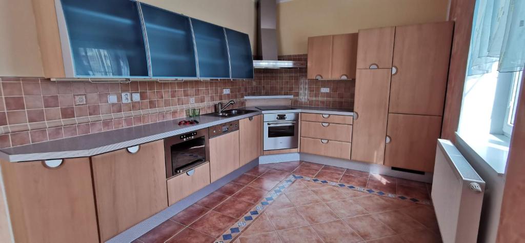 a kitchen with wooden cabinets and a tile floor at Apartmán v centru Jihlavy in Jihlava