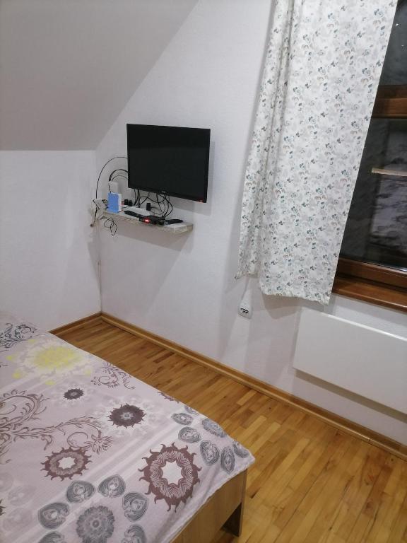 a bedroom with a bed and a tv on the wall at Lodge Zeleni svet in Crni Vrh