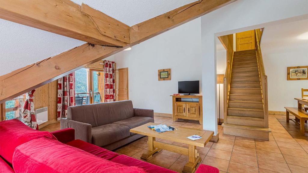 - un salon avec un canapé rouge et une table dans l'établissement Madame Vacances La Cascade, à Vaujany