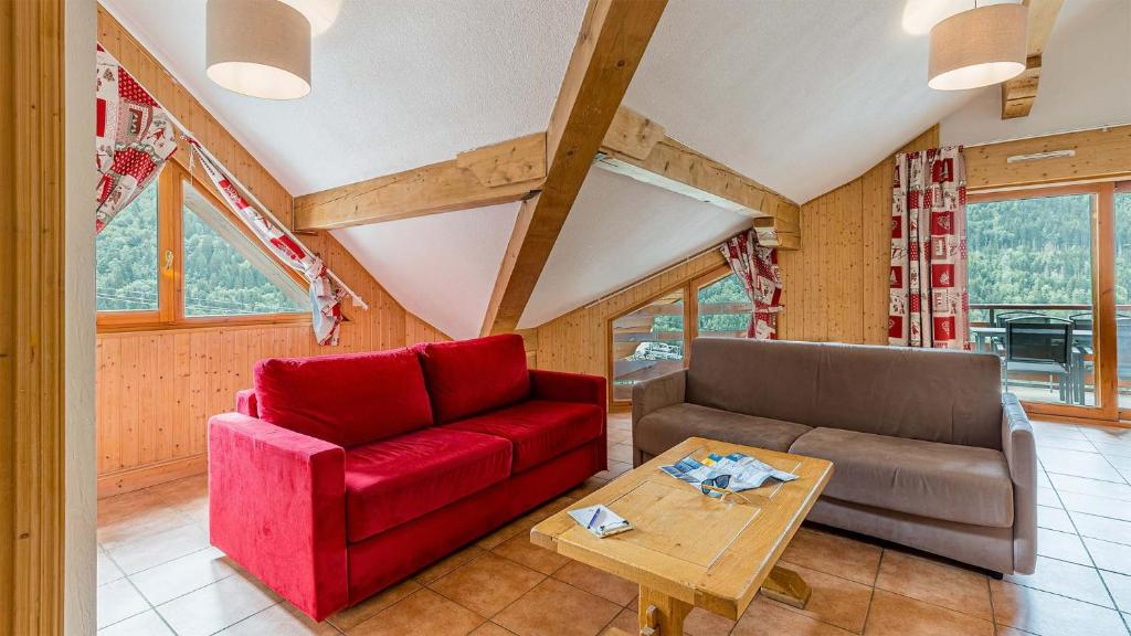 un salon avec un canapé rouge et une table dans l'établissement Madame Vacances La Cascade, à Vaujany
