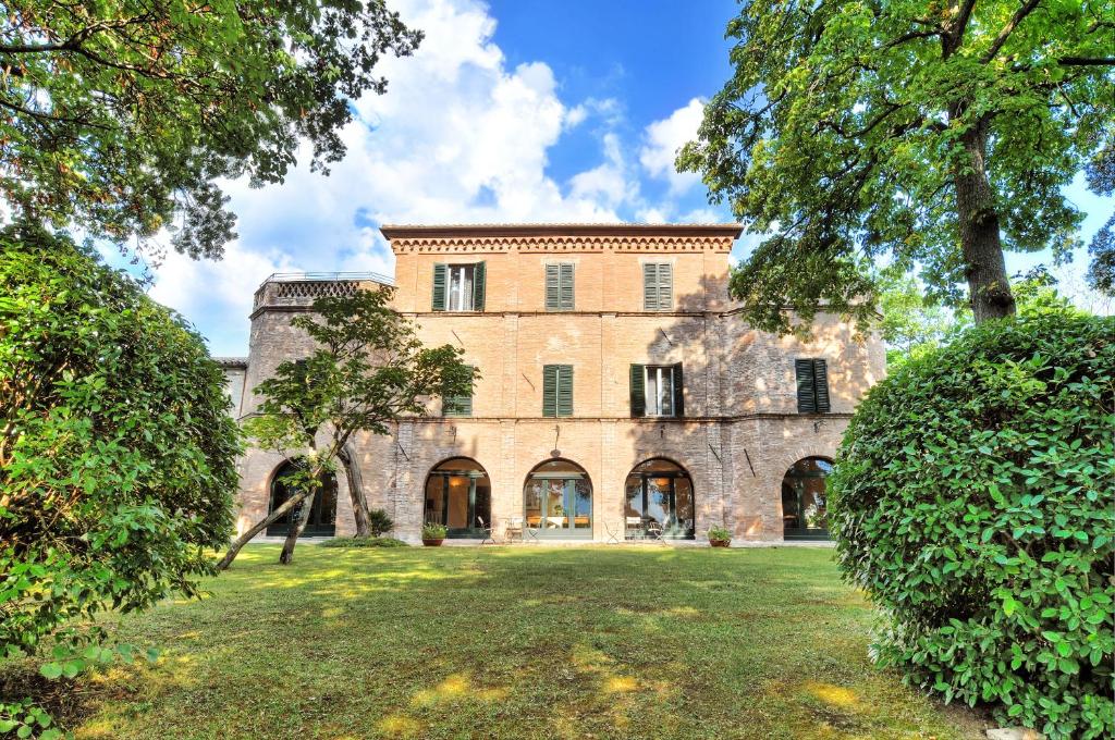 an exterior view of a large stone building with trees at Villa Collepere Country House in Matelica