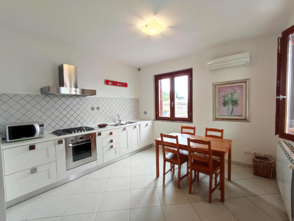 a kitchen with white cabinets and a table and chairs at Casa Vacanza Nuvola in SantʼAntìoco