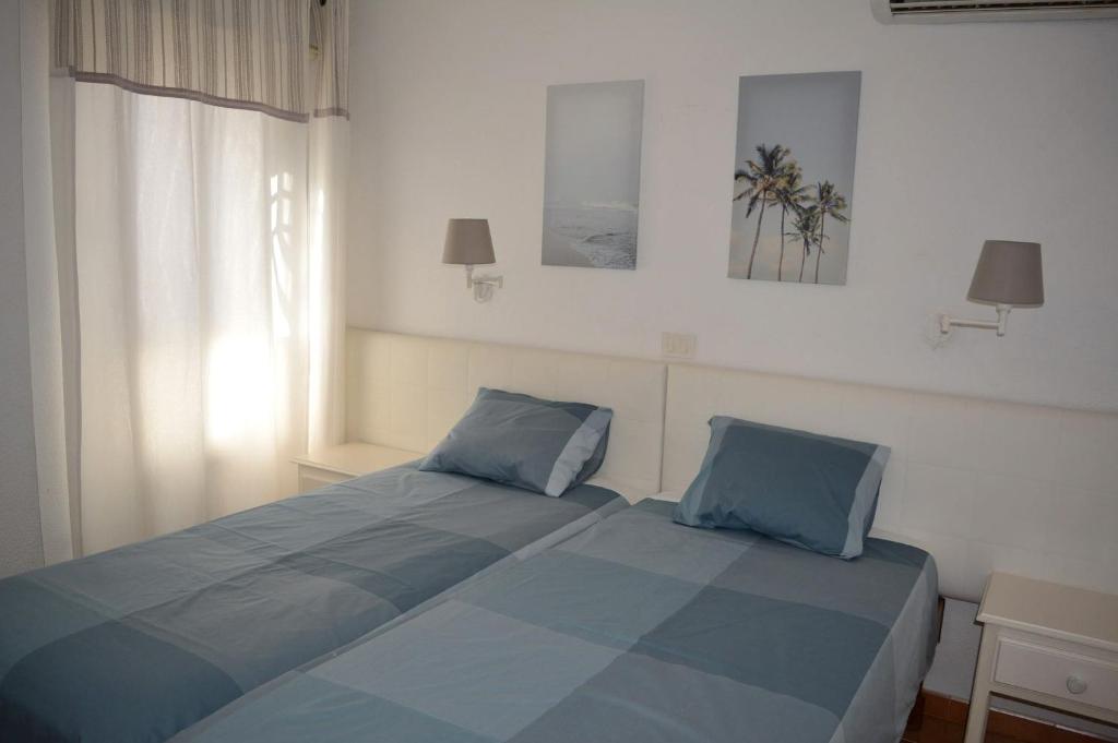a bedroom with a bed with blue sheets and a window at Apartamento IGUAZU in Playa del Ingles