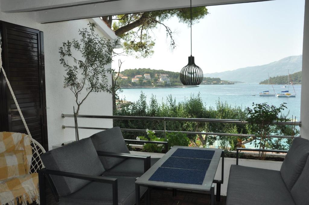 a balcony with a table and chairs and a view of the water at Olive Tree Apartment in Lumbarda