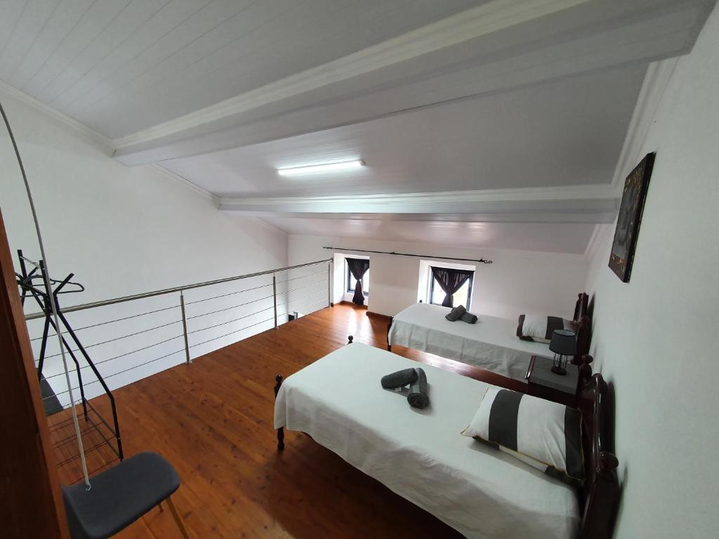 a room with two beds and a wooden floor at Silva House Refuge in Algarvia