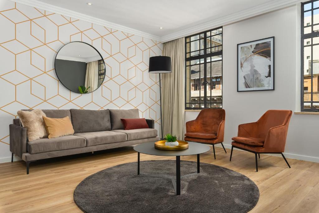 een woonkamer met een bank, een tafel en stoelen bij Mandela Rhodes Luxury Apartments in Kaapstad