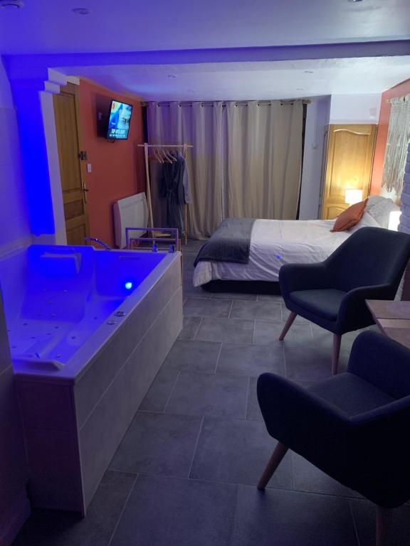 ein Hotelzimmer mit einem Bett und einem blauen Licht in der Unterkunft Studio Cosy avec Jacuzzi Privatif et Terrasse in Hazebrouck