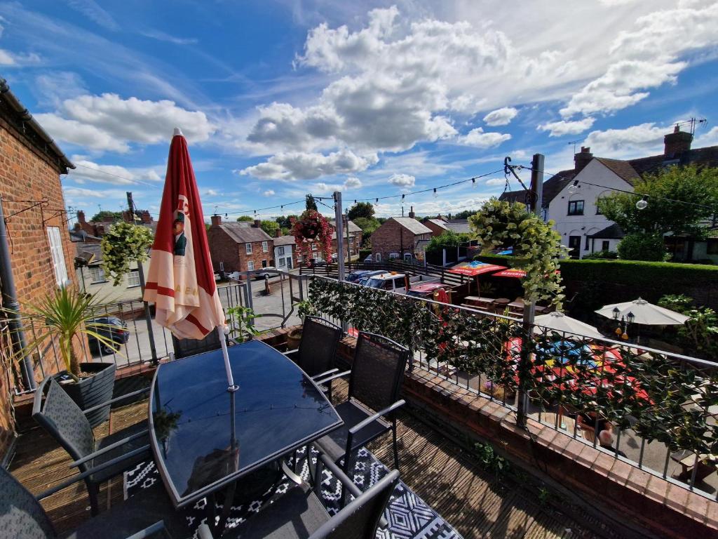 a patio with a table and a umbrella and chairs at The Foresters Arms in Tarporley