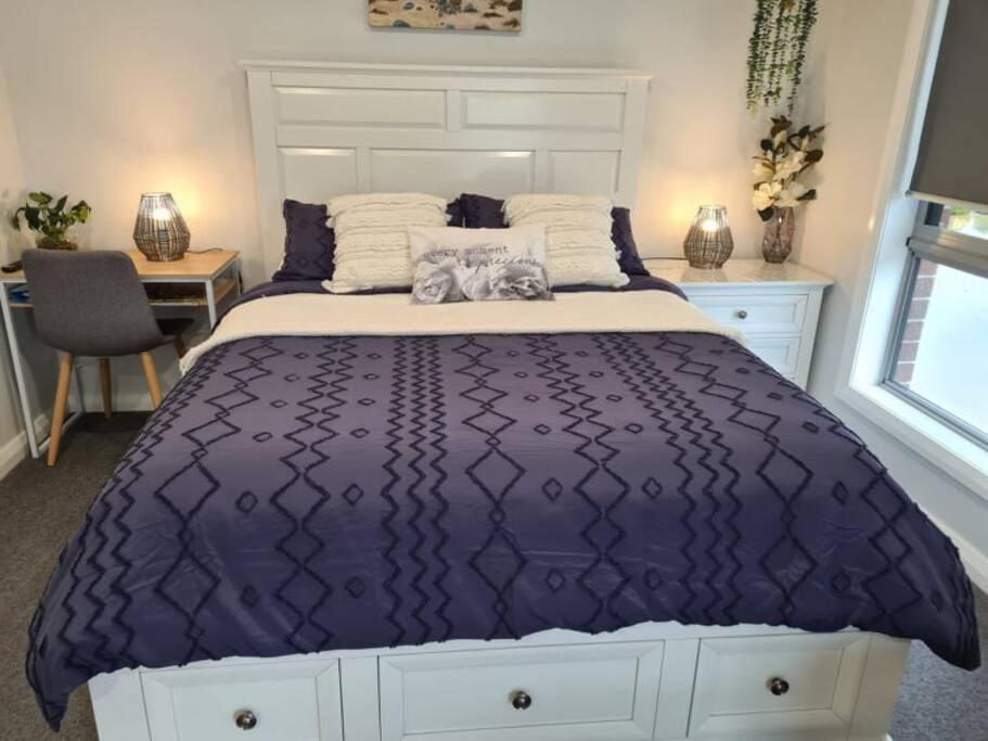 a bed with a purple comforter in a bedroom at Kadi House - Unit 1 in Wynyard