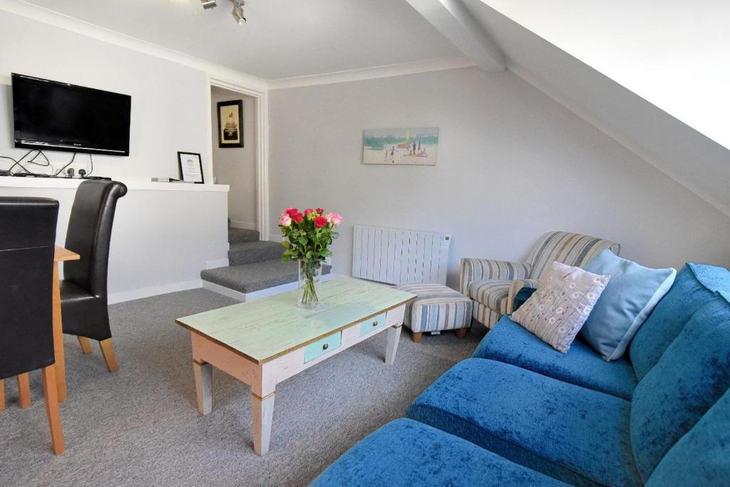 a living room with a blue couch and a table at The Retreat in Lyme Regis