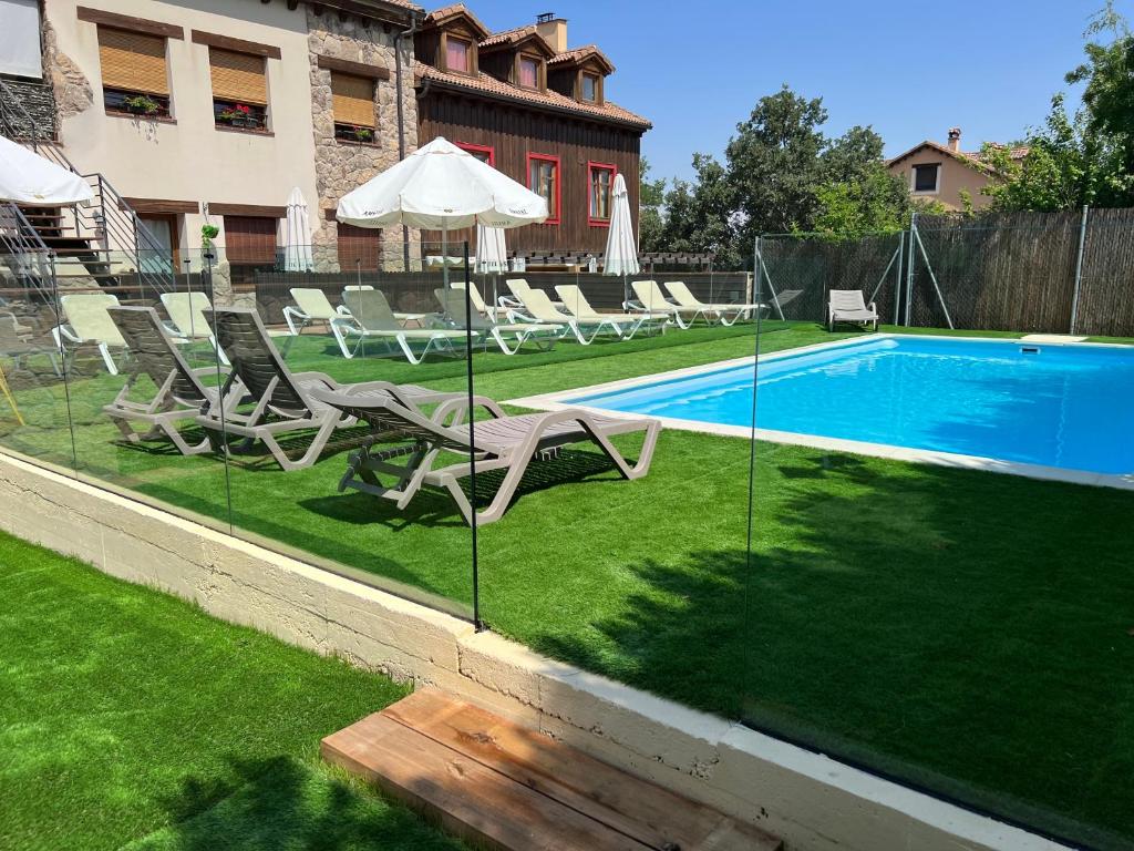 uma piscina com espreguiçadeiras e um guarda-sol em Casa Valsain em La Granja de San Ildefonso