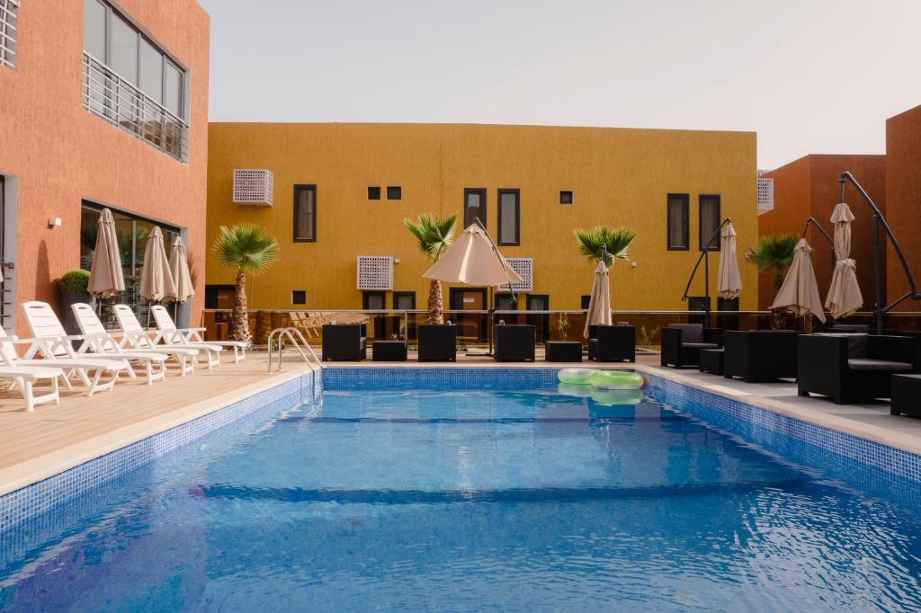 a pool at a hotel with chairs and umbrellas at Marrakech - Premium Suite in Nouakchott