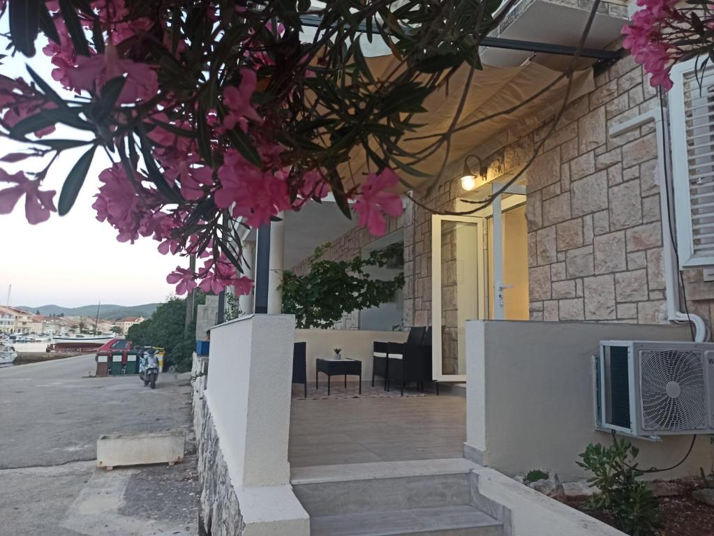 een huis met een veranda met roze bloemen bij Apartman Vranac in Vela Luka