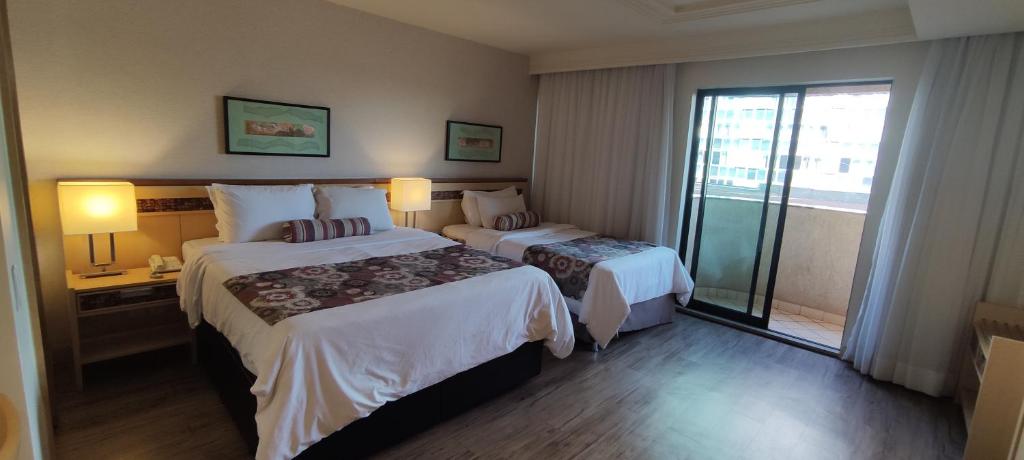 Habitación de hotel con 2 camas y balcón en FLAT DE ALTO PADRÃO - ENORME - CENTRO DA CIDADE - 2 Camas - 1 Queen e 1 Solteiro - Arrumação Diária Gratuita - Excelente Atendimento - VARANDA - COZINHA en Brasilia