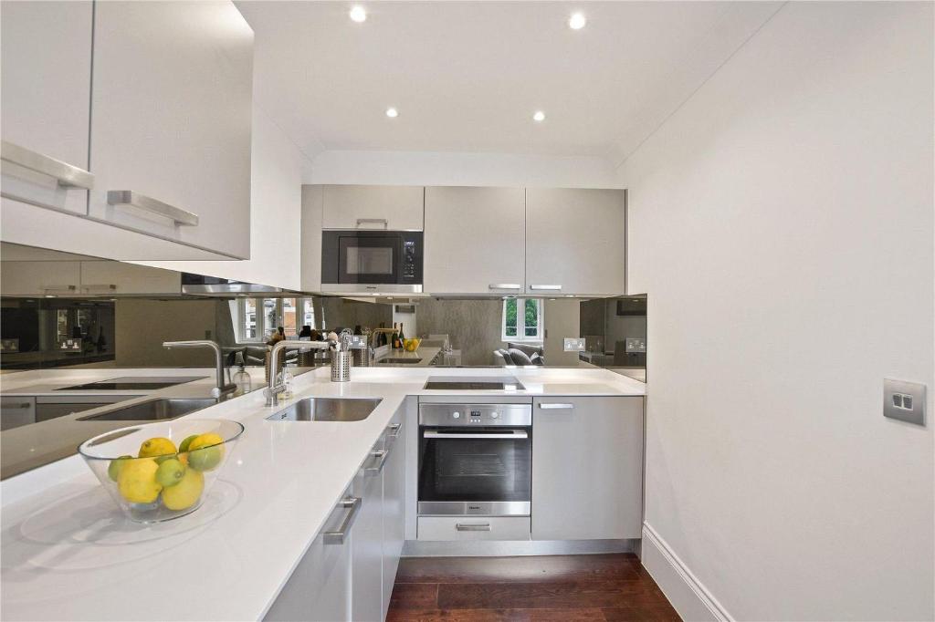 a kitchen with white cabinets and a bowl of fruit on a counter at Famous Piccadilly Circus in London