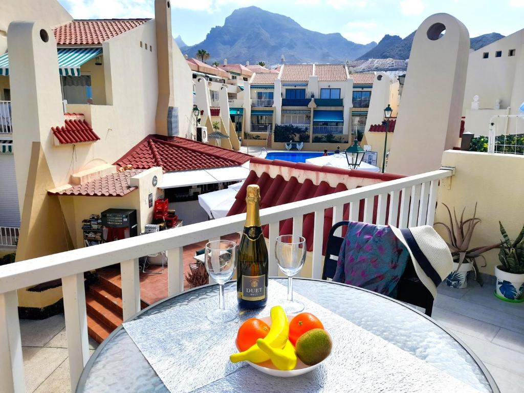 a table with a bottle of wine and fruit on a balcony at Mareverde Elisa, 1 bedroom & Wifi Free in Adeje