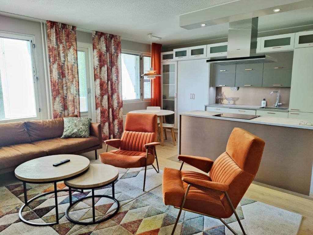 a living room with a couch and chairs and a kitchen at Lovely cityhome in Rovaniemi