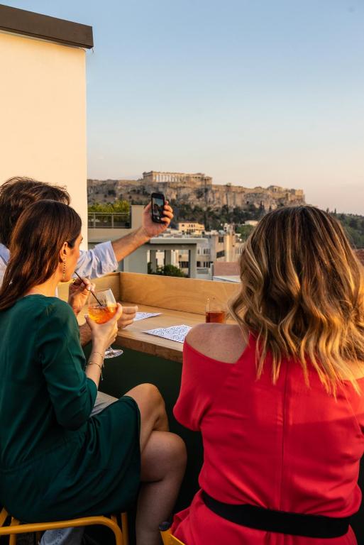 Un uomo che scatta una foto a due donne sedute a un tavolo di Mosaikon ad Atene