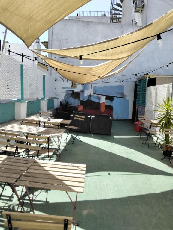 un patio con mesas, sillas y una hamaca en Rosa de los Vientos en Cádiz