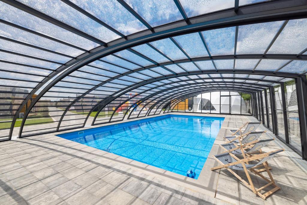 an overhead view of a swimming pool with a glass ceiling at RResort - nowe KLIMATYZOWANE domki z PODGRZEWANYM Basenem, Sauna, WiFi, parking w cenie! in Rewal