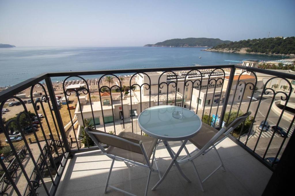 balcón con mesa, sillas y vistas al océano en Hotel Svarog, en Bečići